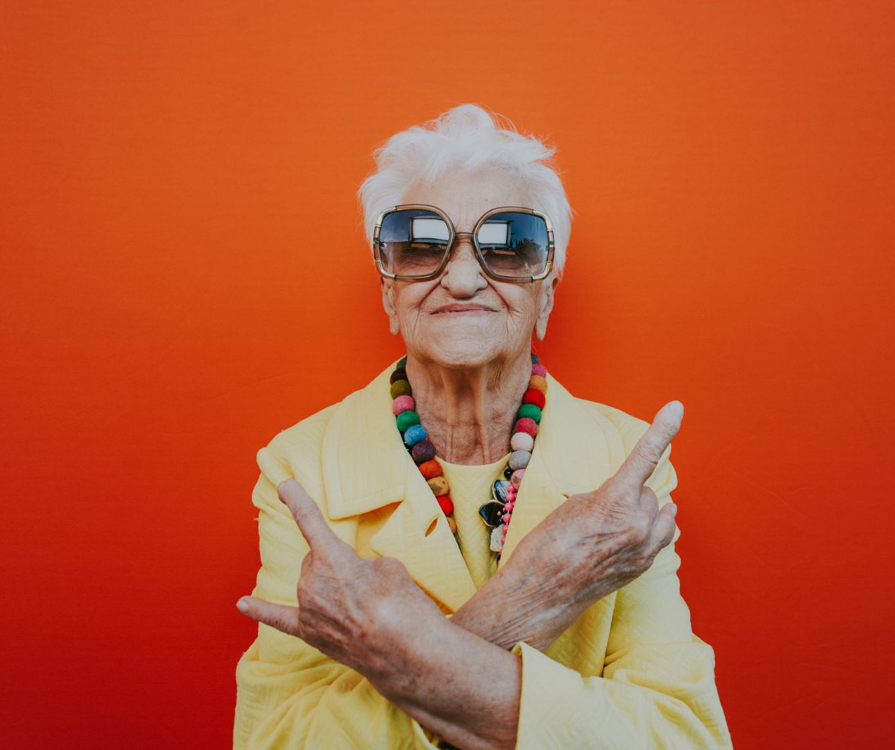 Flippige Seniorin mit lebhaftem, buntem Armschmuck, strahlt Lebensfreude und Individualität aus.