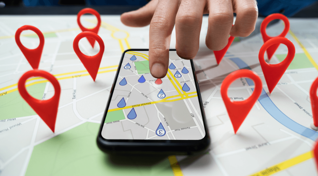 Ein Smartphone auf einer gedruckten Karte mit mehreren 3D-roten Standortmarkern, die auf die Karte zeigen.
